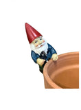A painted garden gnome pot sitter figurine with a red hat, white beard, blue coat, and green pants, shown beside a terracotta pot on a plain white background.