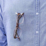 Stainless Steel Magnetic Eye Glasses Holder shown in use on a shirt - by Readerest. Just Clip the magnetic backing and front hanger to your closes and hang your glasses. Also use to hold earphone cables and badges.