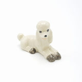 Laying white poodle figurine - A pretty white poodle with gray markings that is part of our extensive dog range.  As our ceramic animals are handcrafted and handpainted, size, colour and markings may vary.  This ceramic collectable figurine measures approx :  Laying 6.8cm x 3cm x 4.5cm high.  Made in Thailand.