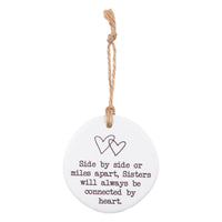 Side by Side or miles apart, Sisters will always be connected by heart. Tiny Treasures ceramic disc with rope hanging